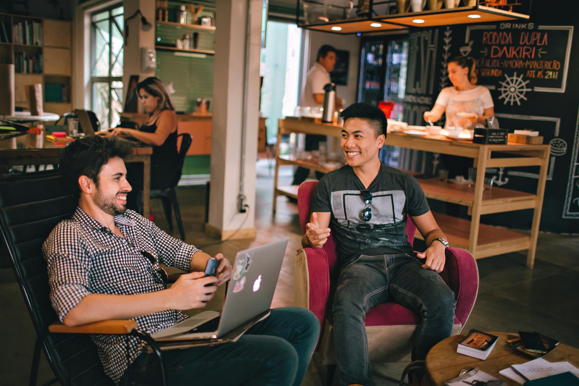A man sitting in a chair next to another man on a laptop